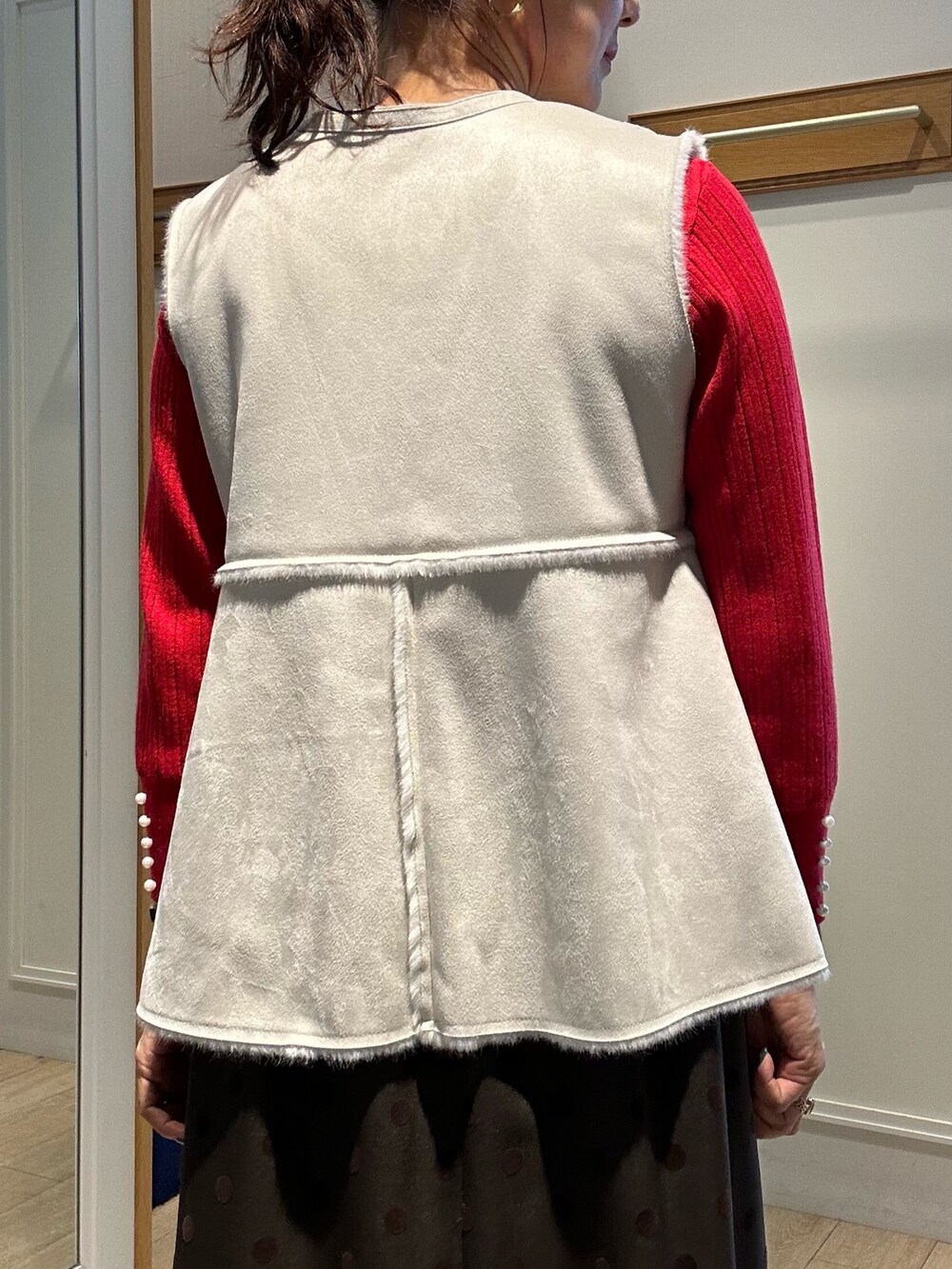 レッド系のニット/セーター、ブラウン系のスカート、ブラック系のトートバッグを着用したレディースの秋コーディネートの10枚目の写真