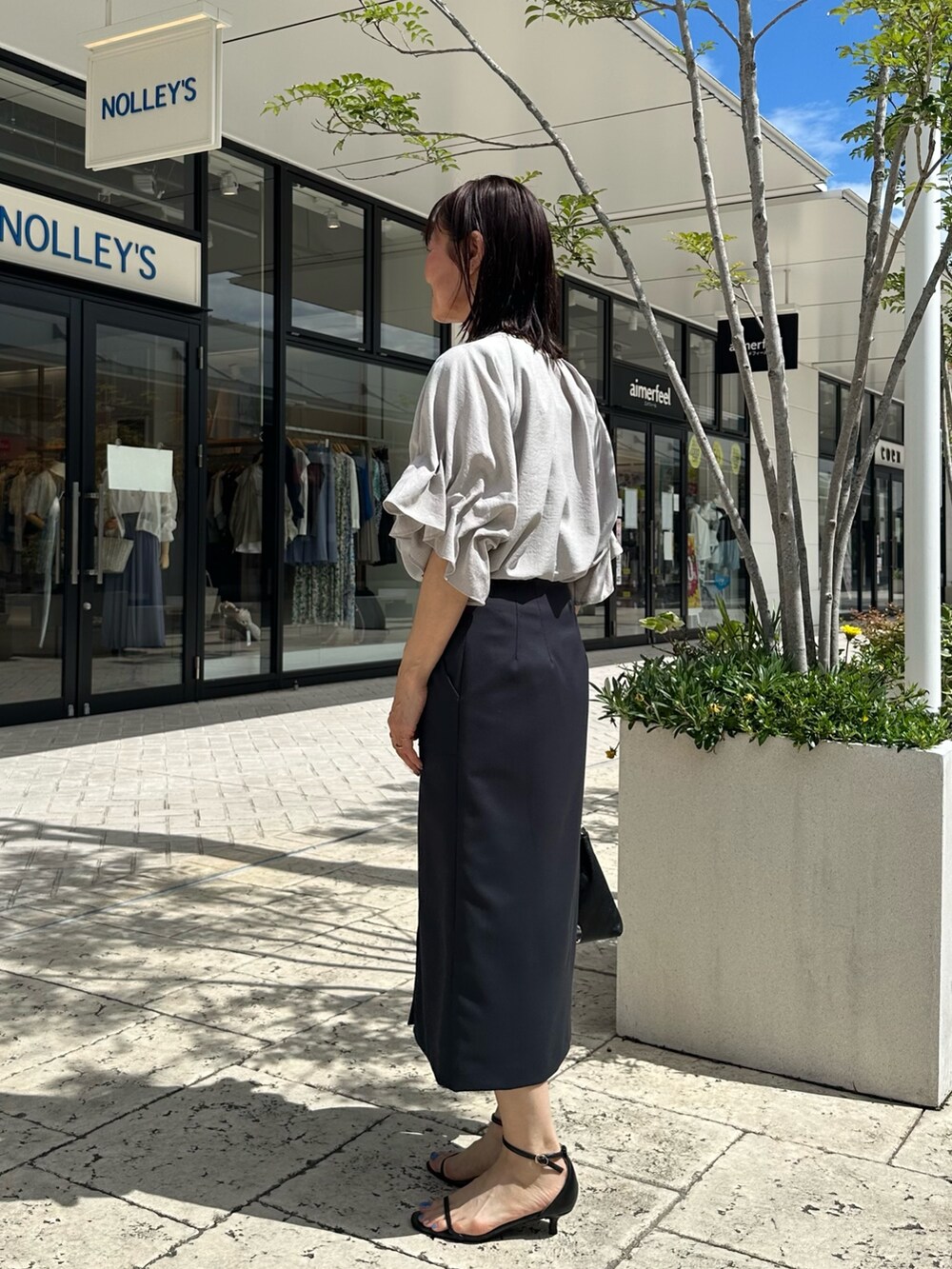 ブラック系のサンダル、ベージュ系のシャツ/ブラウス、ブルー系のスカートを着用したレディースの夏コーディネートの2枚目の写真