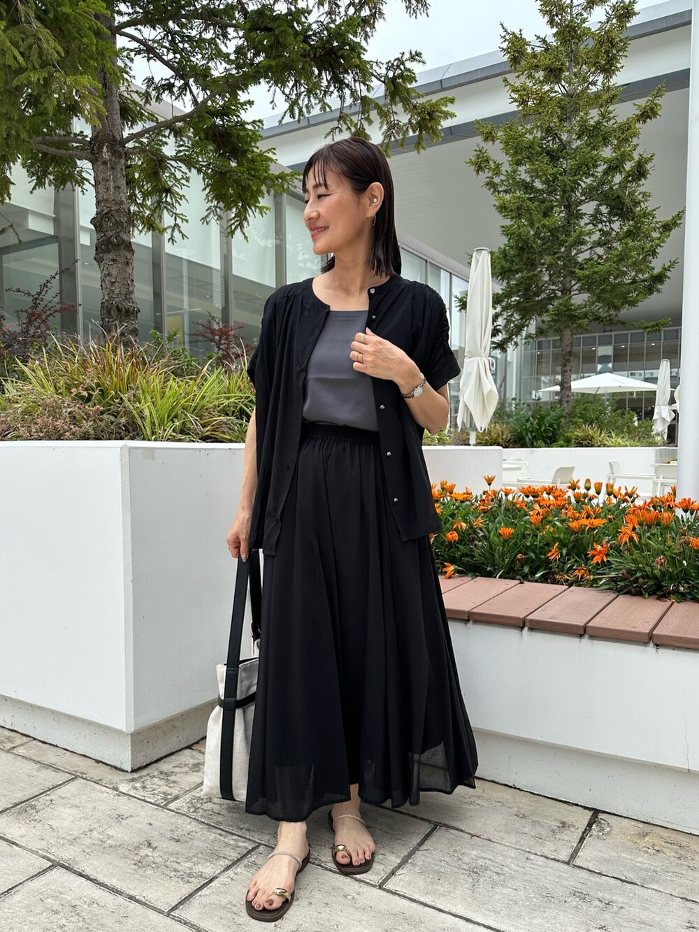 ブラック系のシャツ/ブラウス、ブラック系のスカート、ゴールド系のネックレスを着用したレディースの夏コーディネートの5枚目の写真