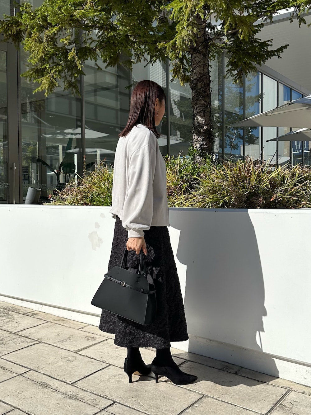 グレー系のブルゾン、ブラック系のニット/セーター、グレー系のスカートを着用したレディースの秋コーディネートの4枚目の写真