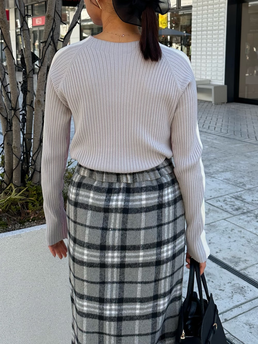 グレー系のスカート、ブラック系のトートバッグ、ピンク系のニット/セーターを着用したレディースの秋コーディネートの7枚目の写真