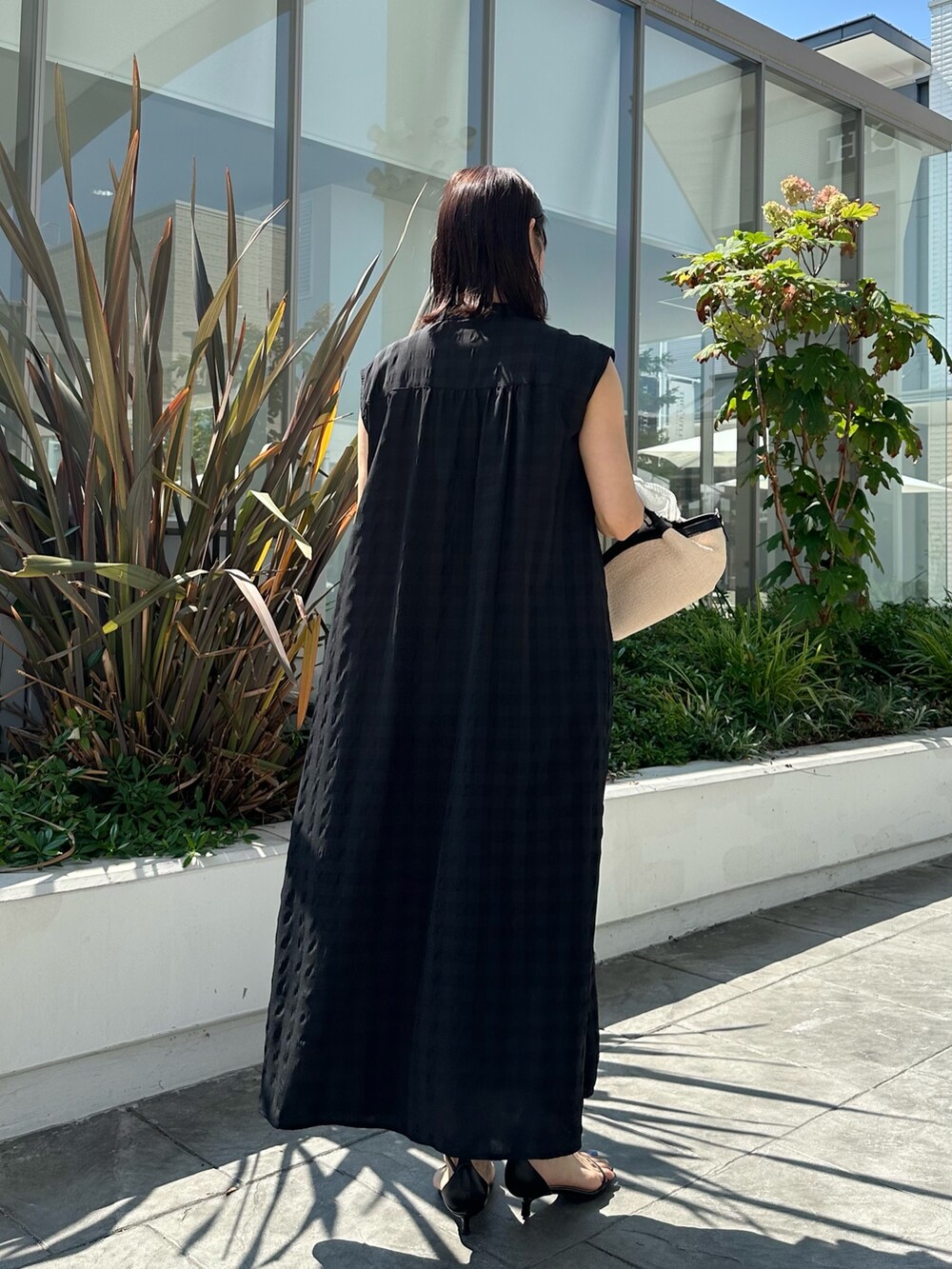 ブラック系のワンピース、ホワイト系のカーディガン/ボレロ、ブラック系のバックパック/リュックを着用したレディースの夏コーディネートの9枚目の写真