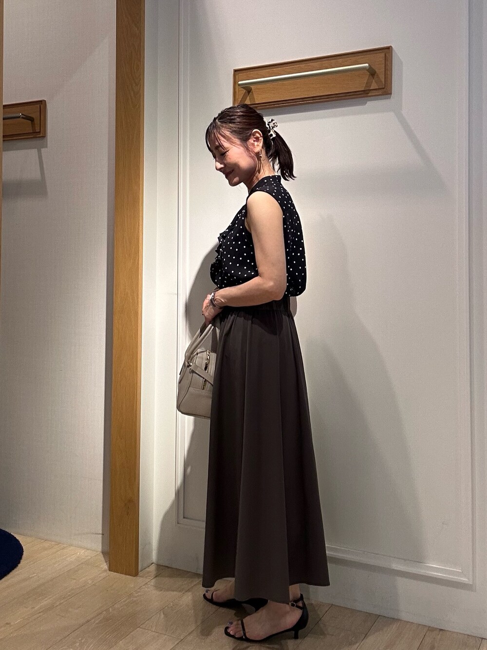 ブラック系のシャツ/ブラウス、グレー系のスカート、ベージュ系のボストンバッグを着用したレディースの夏コーディネートの4枚目の写真