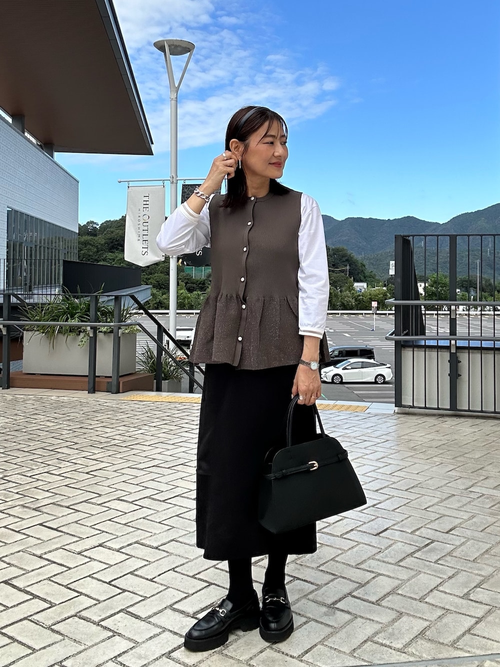 ホワイト系のTシャツ/カットソー、ブラック系のスカート、ブラウン系のニット/セーターを着用したレディースの秋コーディネートの3枚目の写真