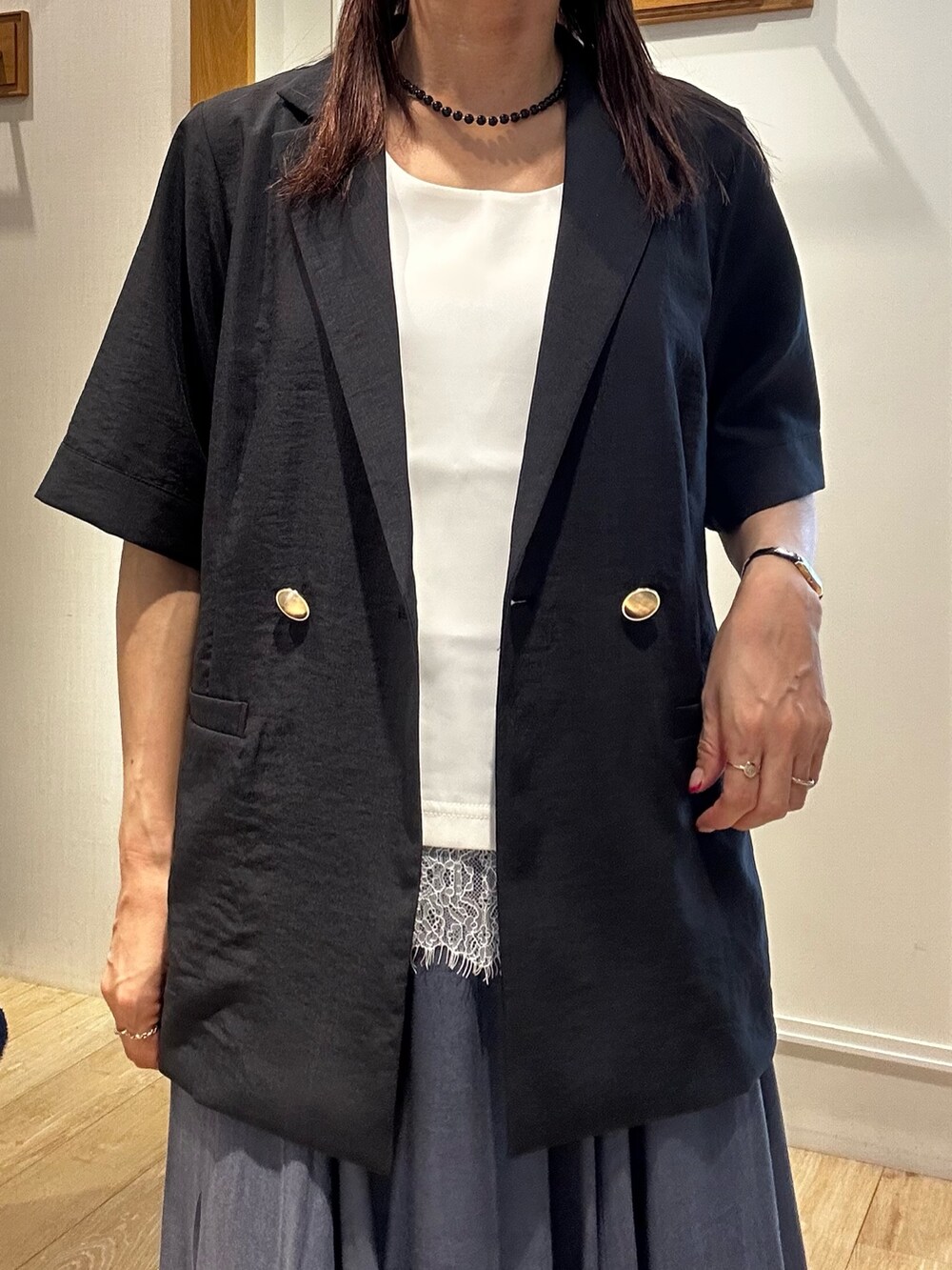 グレー系のテーラードジャケット、ホワイト系のTシャツ/カットソー、ブルー系のスカートを着用したレディースの夏コーディネートの4枚目の写真