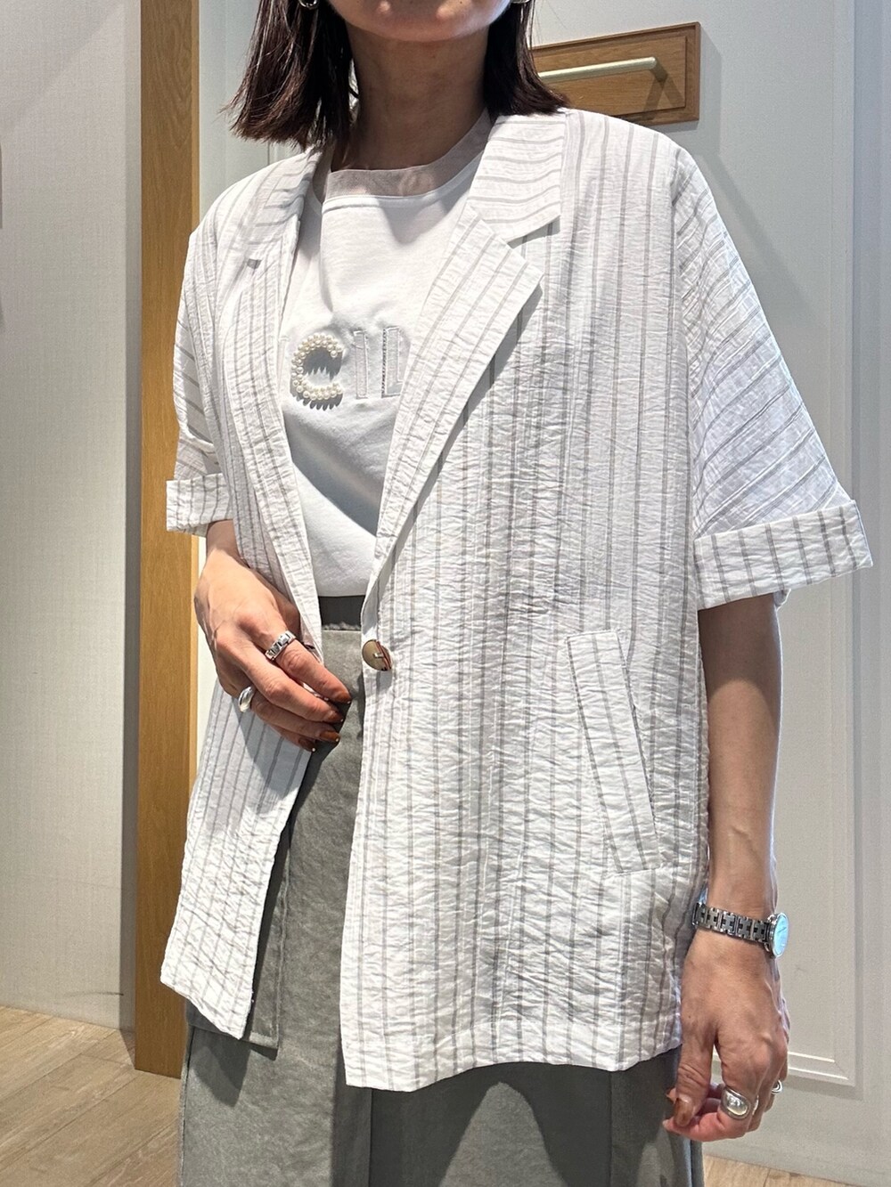 グレー系のテーラードジャケット、ホワイト系のTシャツ/カットソー、グリーン系のスカートを着用したレディースの夏コーディネートの5枚目の写真