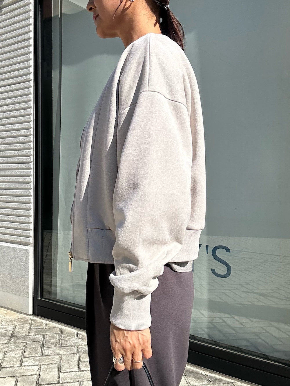グレー系のその他パンツ、グレー系のニット/セーター、ベージュ系のブルゾンを着用したレディースの秋コーディネートの6枚目の写真