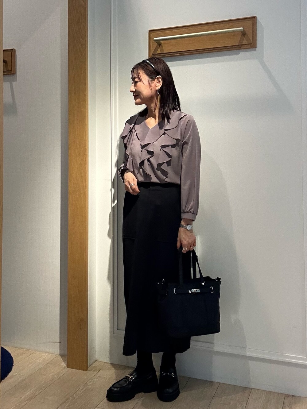 ブラウン系のシャツ/ブラウス、ブラック系のスカート、ブラック系のトートバッグを着用したレディースの秋コーディネートの6枚目の写真