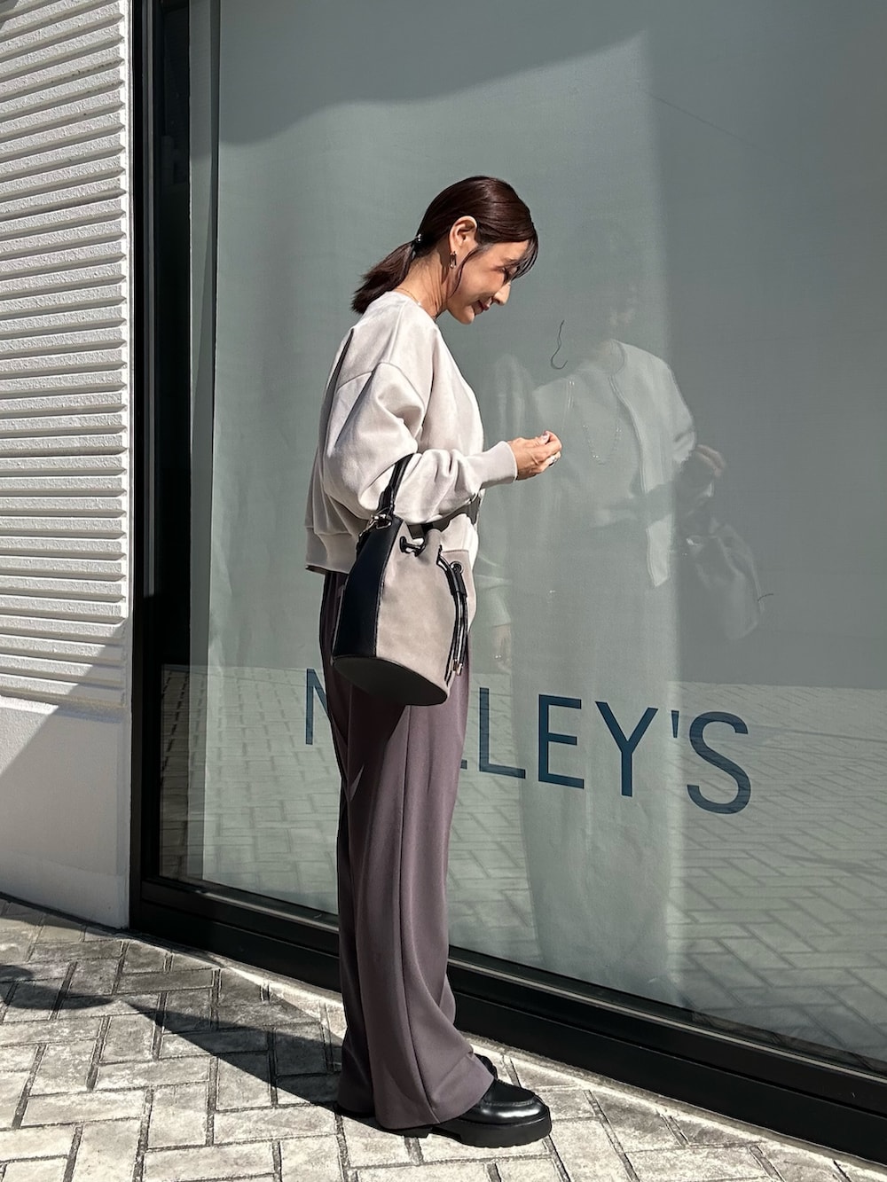 グレー系のその他パンツ、グレー系のニット/セーター、ベージュ系のブルゾンを着用したレディースの秋コーディネートの4枚目の写真