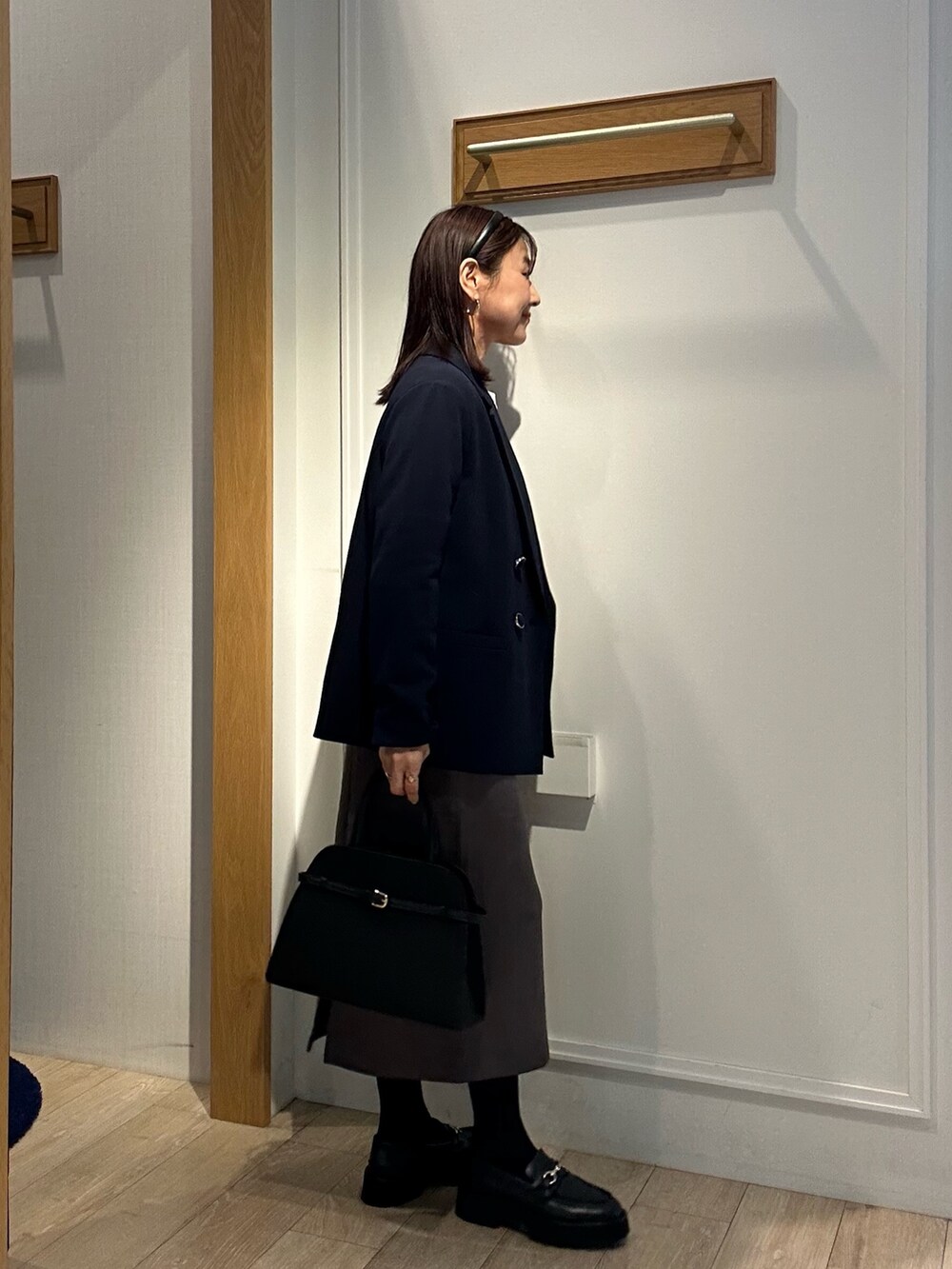 ホワイト系のニット/セーター、ブルー系のテーラードジャケット、グレー系のスカートを着用したレディースの秋コーディネートの4枚目の写真