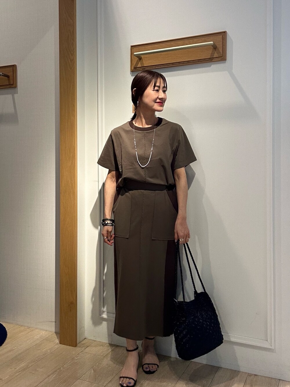 ブラウン系のTシャツ/カットソー、ブラウン系のスカート、ブラック系のサンダルを着用したレディースの夏コーディネートの4枚目の写真