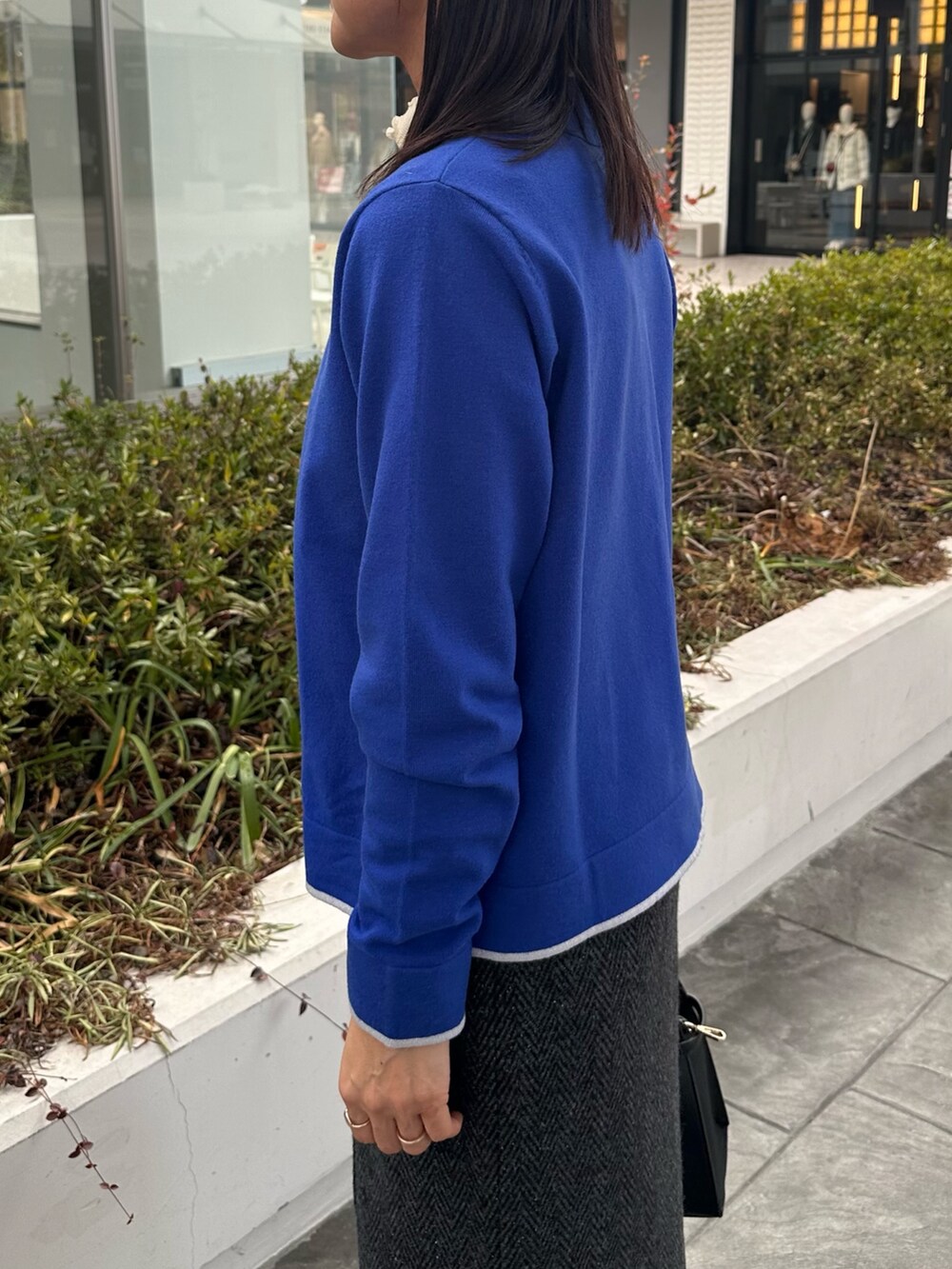 ブルー系のカーディガン/ボレロ、グレー系のスカート、ブラック系のトートバッグを着用したレディースの冬コーディネートの5枚目の写真