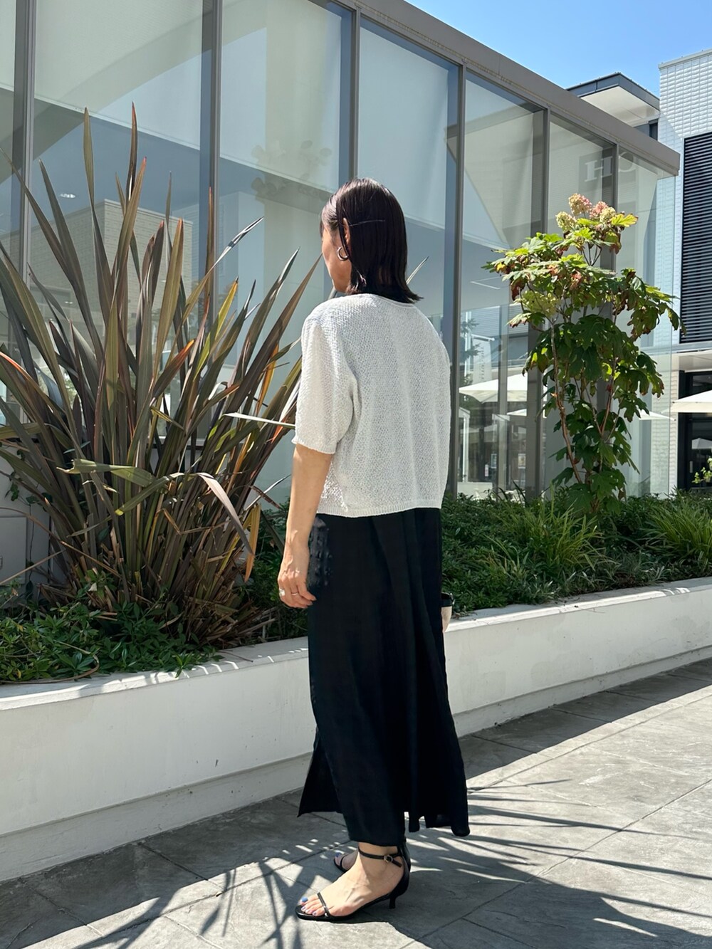 ブラック系のワンピース、ホワイト系のカーディガン/ボレロ、ブラック系のバックパック/リュックを着用したレディースの夏コーディネートの2枚目の写真