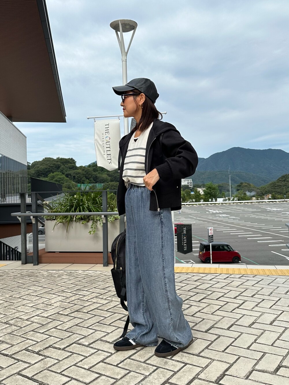 ブラック系のパーカー、ブルー系のデニムパンツ、ブラック系のバックパック/リュックを着用したレディースの秋コーディネートの3枚目の写真