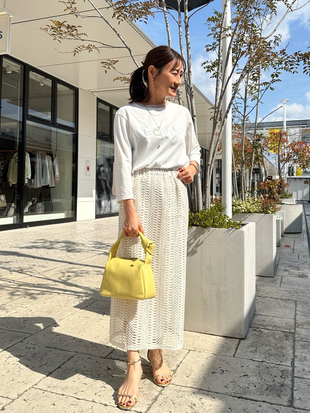 ブルー系のテーラードジャケット、ホワイト系のスカート、イエロー系のショルダーバッグを着用したレディースの春コーディネートの8枚目の写真
