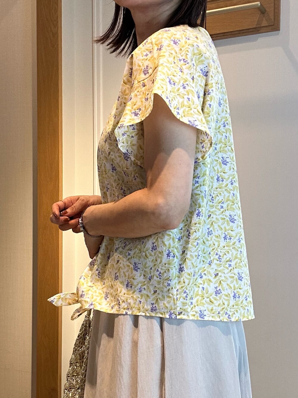 ホワイト系のスカート、イエロー系のシャツ/ブラウス、ゴールド系のネックレスを着用したレディースの春コーディネートの5枚目の写真