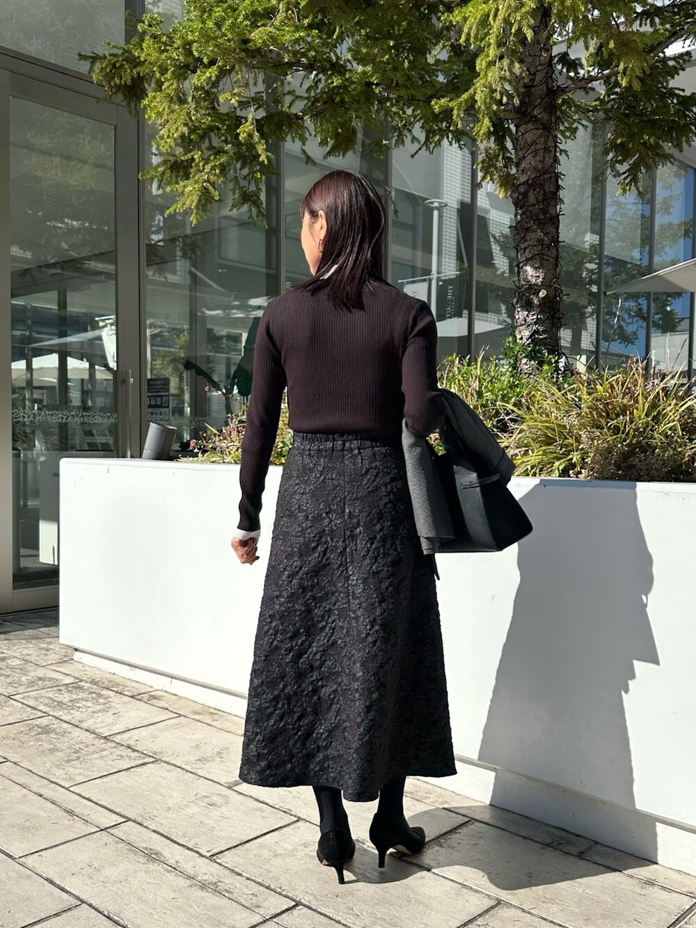 ブラック系のトートバッグ、グレー系のテーラードジャケット、ブラック系のニット/セーターを着用したレディースの秋コーディネートの3枚目の写真