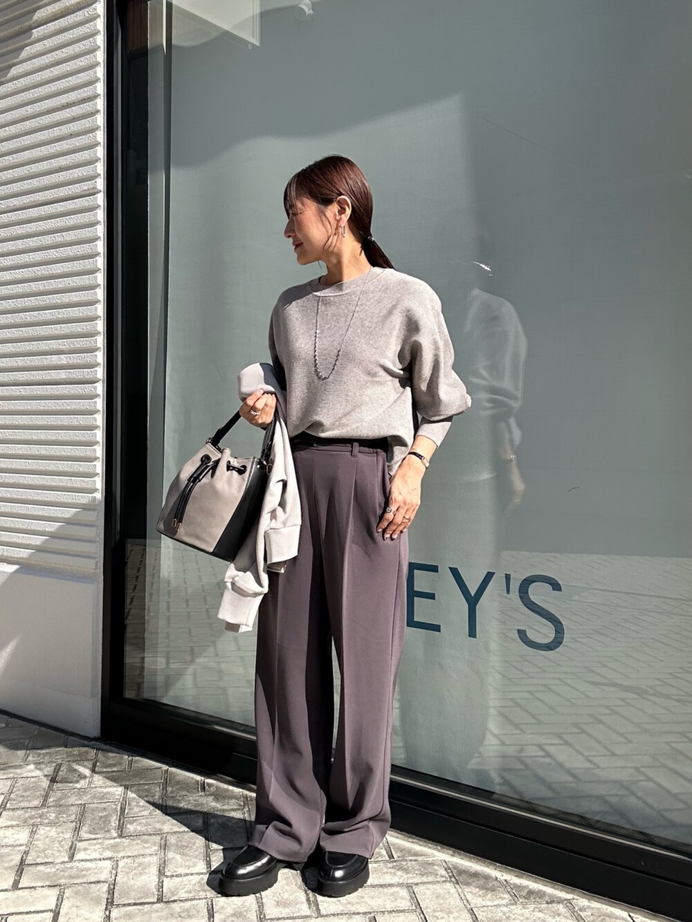 グレー系のその他パンツ、グレー系のニット/セーター、ベージュ系のブルゾンを着用したレディースの秋コーディネートの9枚目の写真