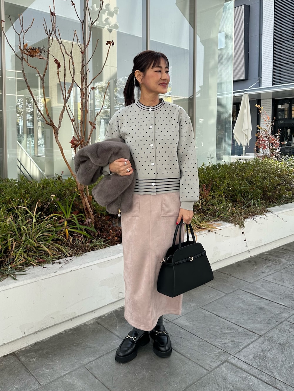 グレー系のブルゾン、グレー系のニット/セーター、ピンク系のスカートを着用したレディースの冬コーディネートの7枚目の写真
