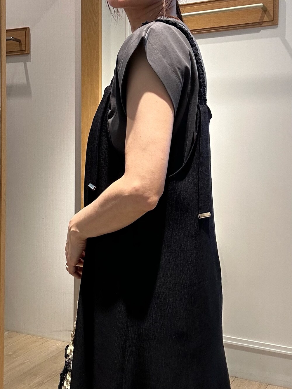 ブラック系のワンピース、ホワイト系のカーディガン/ボレロ、ゴールド系のネックレスを着用したレディースの夏コーディネートの6枚目の写真