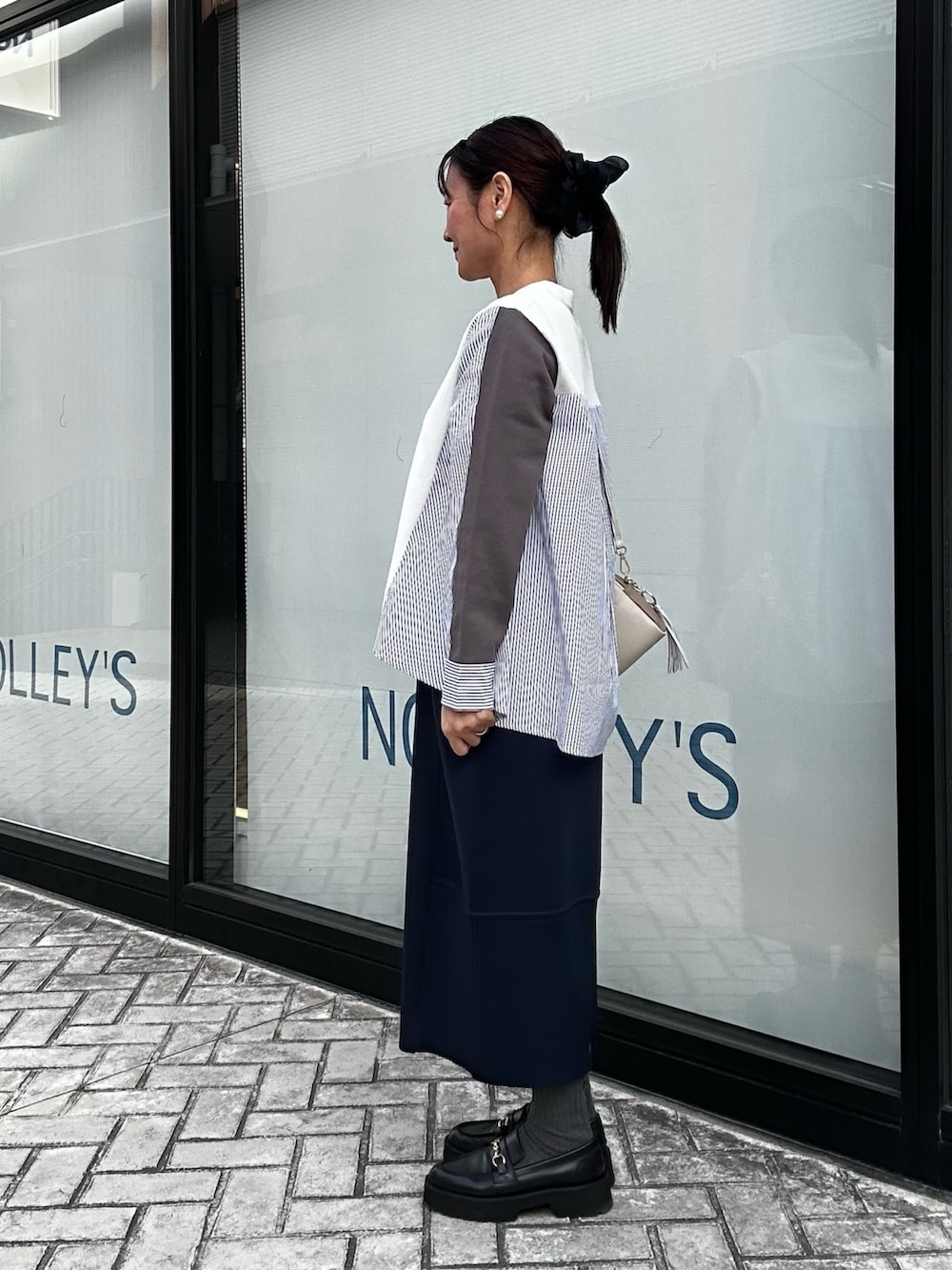 ブルー系のスカート、ホワイト系のニット/セーター、ホワイト系のショルダーバッグを着用したレディースの冬コーディネートの2枚目の写真