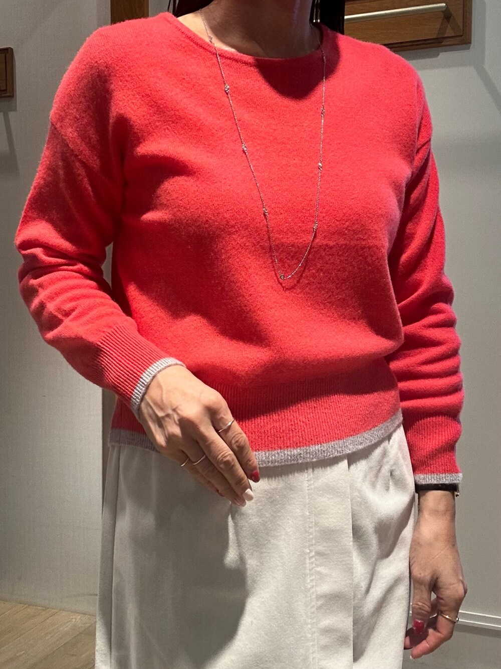 ピンク系のニット/セーター、ホワイト系のスカート、グレー系のダウンジャケット/コートを着用したレディースの冬コーディネートの4枚目の写真