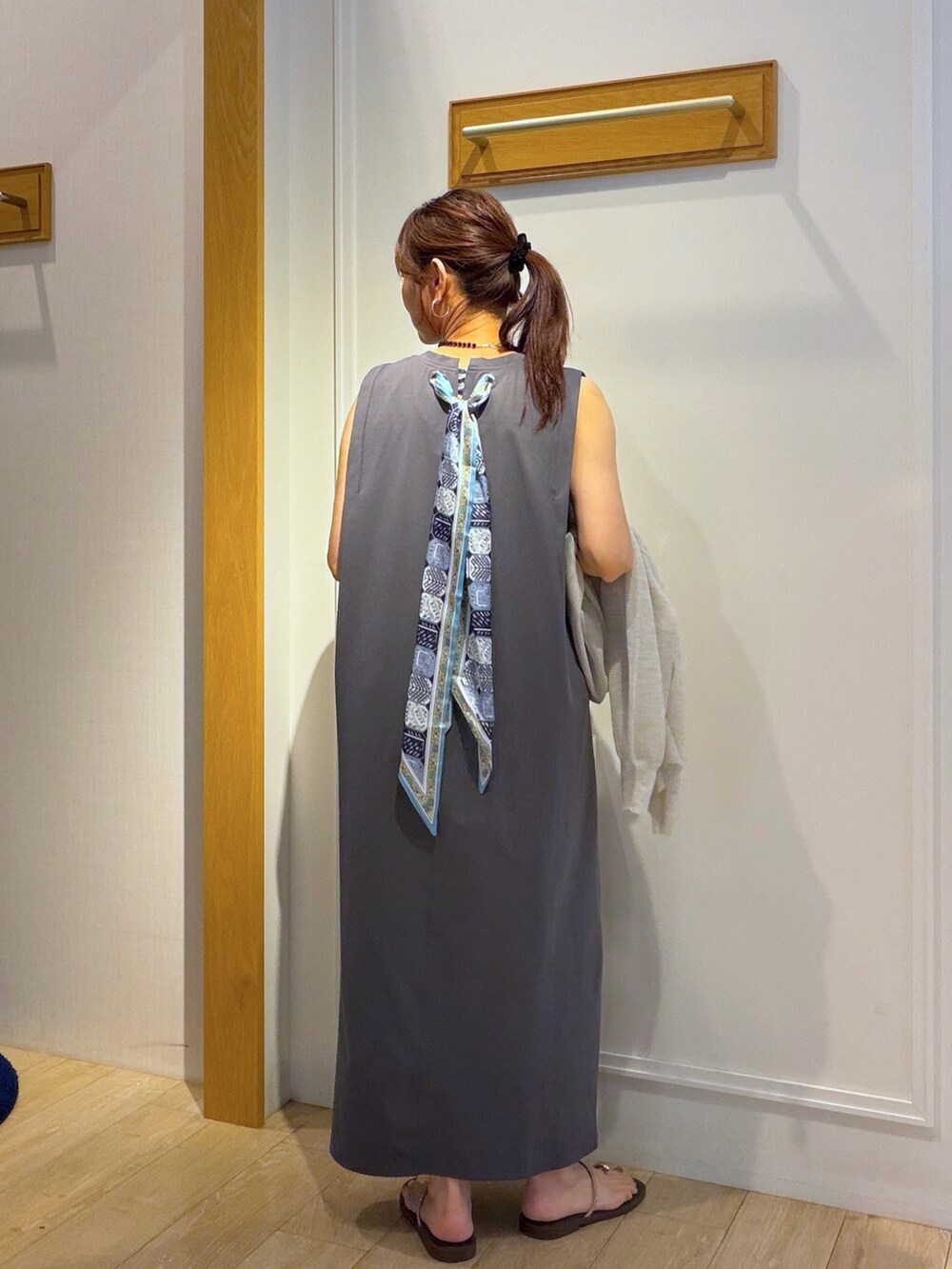 ベージュ系のカーディガン/ボレロ、グレー系のワンピース、ブラック系のネックレスを着用したレディースの夏コーディネートの7枚目の写真