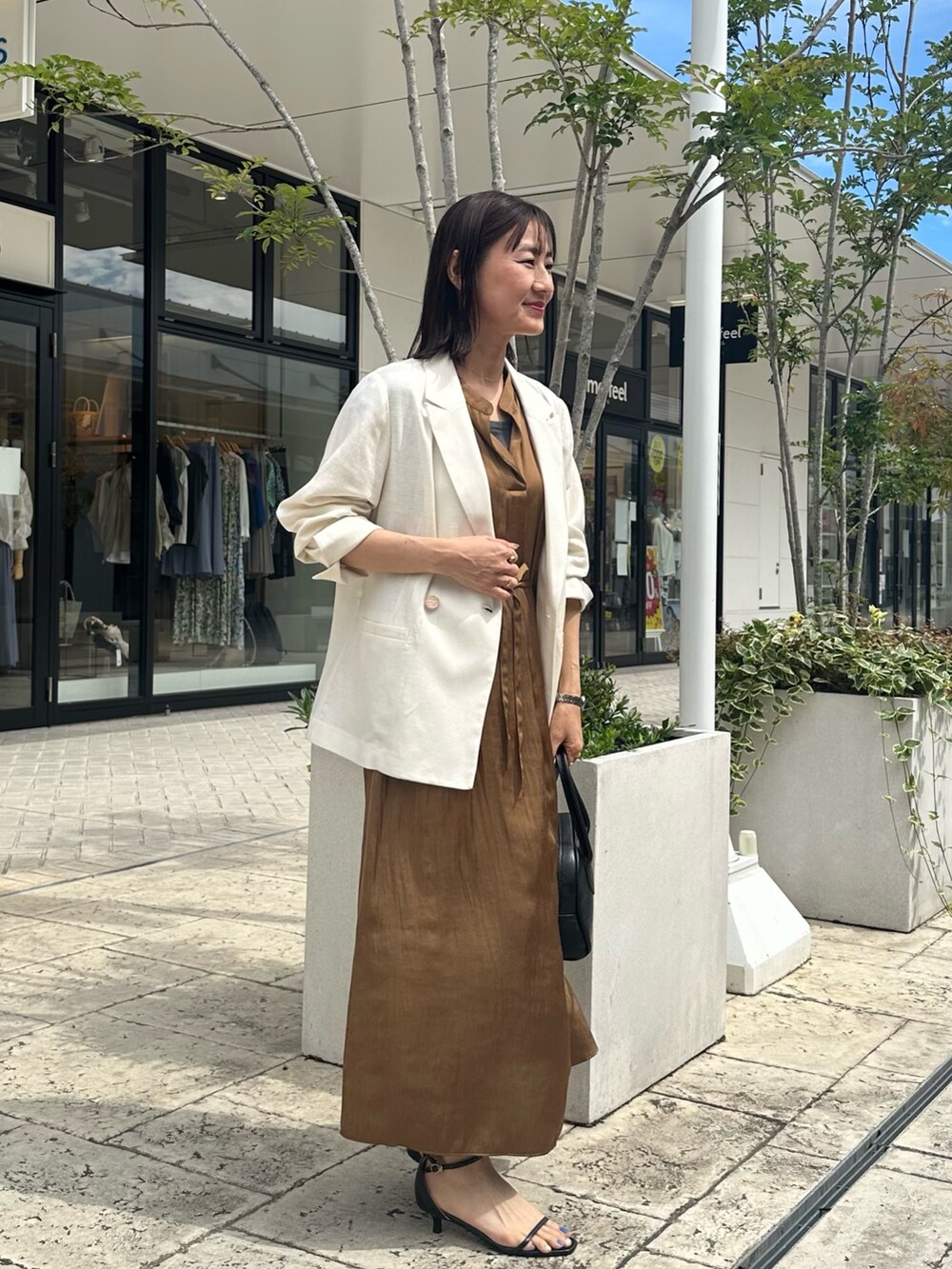ブラウン系のワンピース、グレー系のTシャツ/カットソー、ホワイト系のテーラードジャケットを着用したレディースの夏コーディネートの2枚目の写真