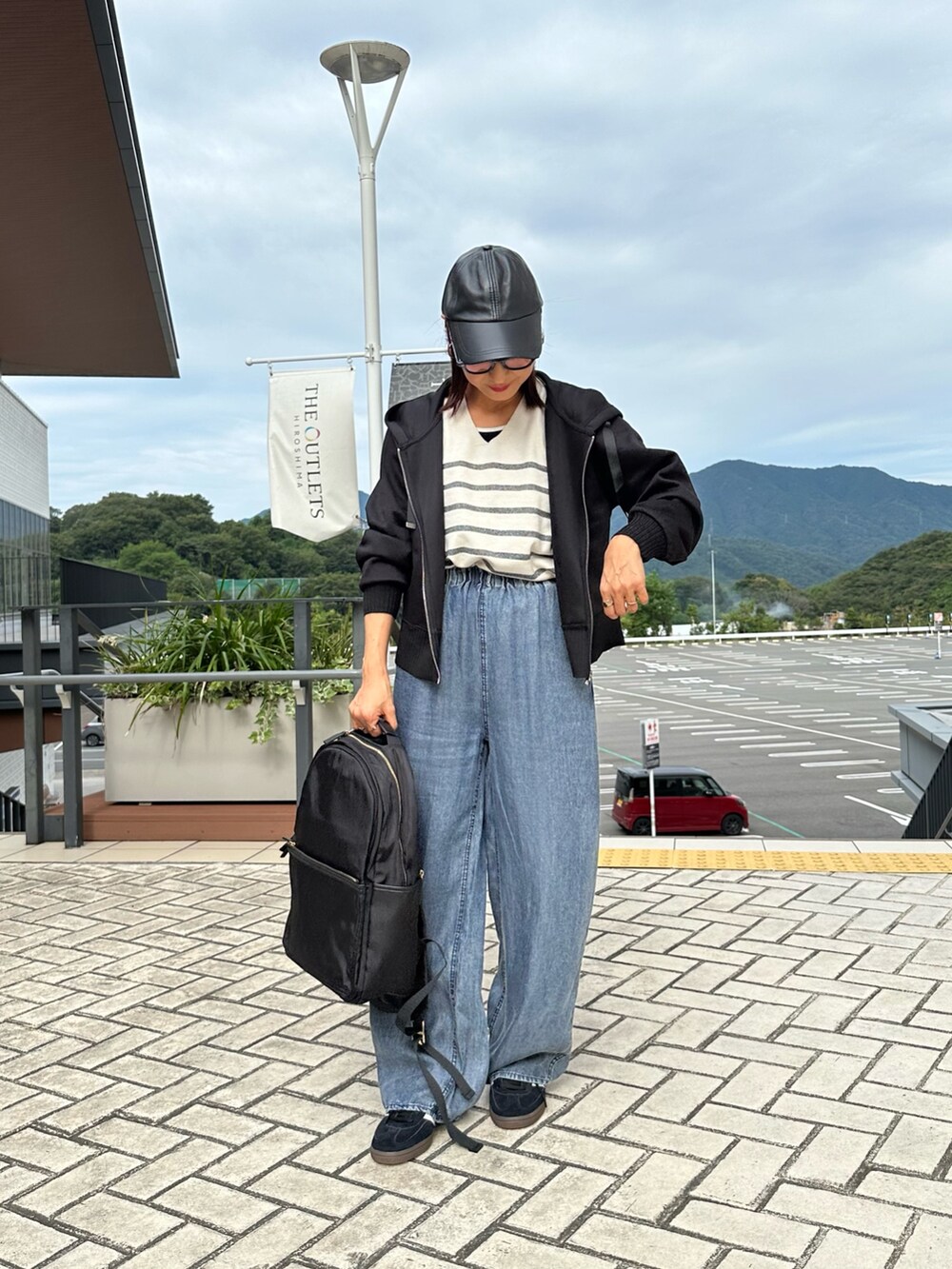 ブラック系のパーカー、ブルー系のデニムパンツ、ブラック系のバックパック/リュックを着用したレディースの秋コーディネートの2枚目の写真