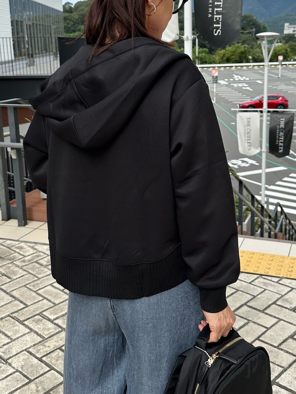 ブラック系のパーカー、ブルー系のデニムパンツ、ブラック系のバックパック/リュックを着用したレディースの秋コーディネートの8枚目の写真