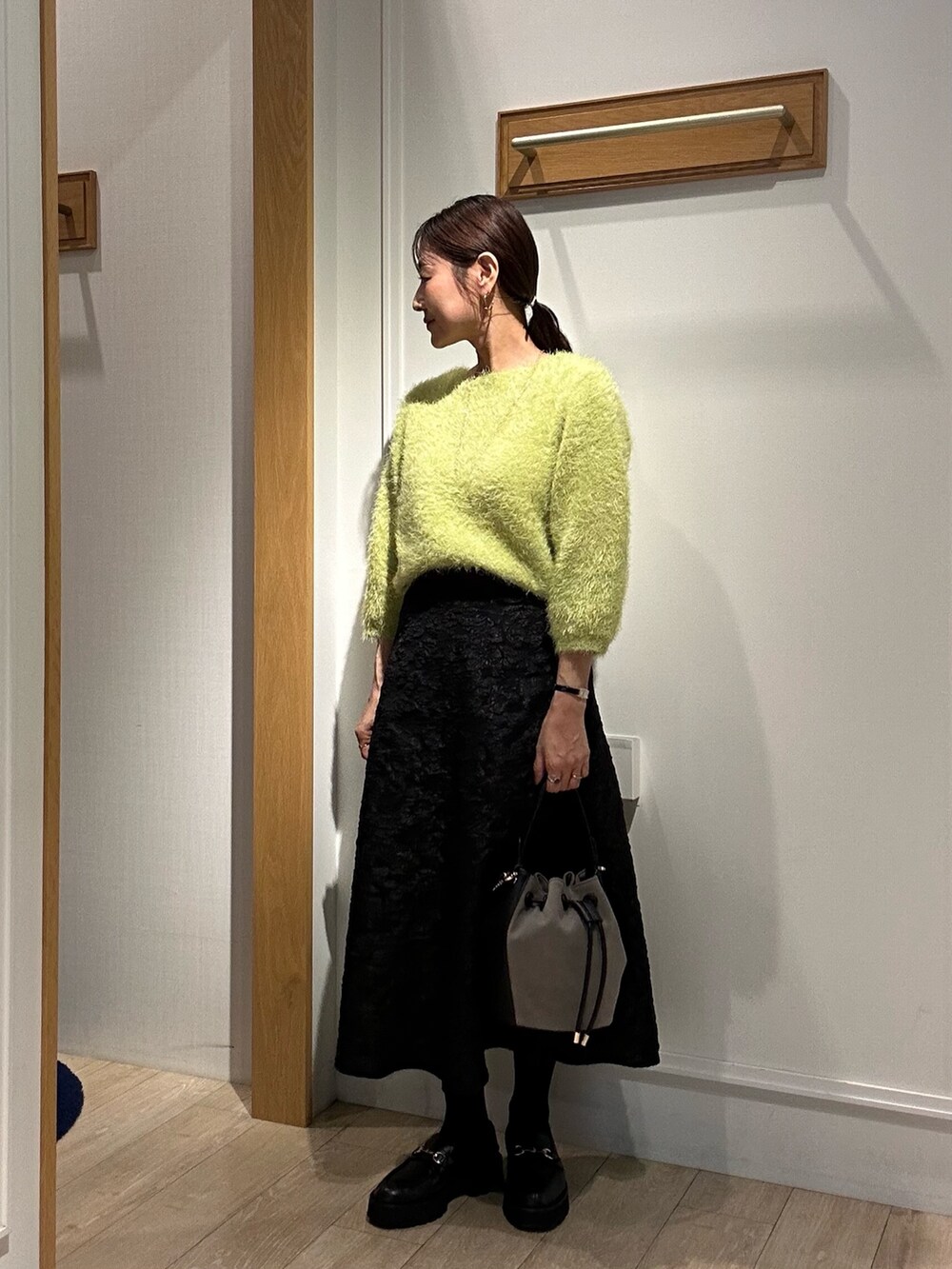 グリーン系のニット/セーター、グレー系のスカート、イエロー系のブルゾンを着用したレディースの秋コーディネートの2枚目の写真