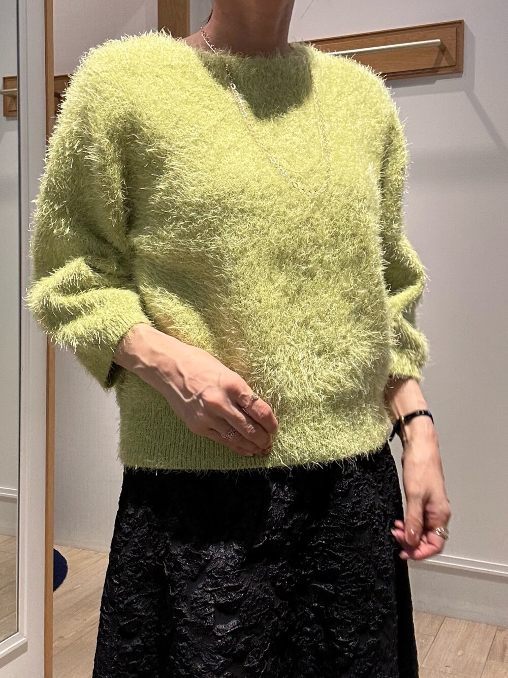 グリーン系のニット/セーター、グレー系のスカート、イエロー系のブルゾンを着用したレディースの秋コーディネートの5枚目の写真