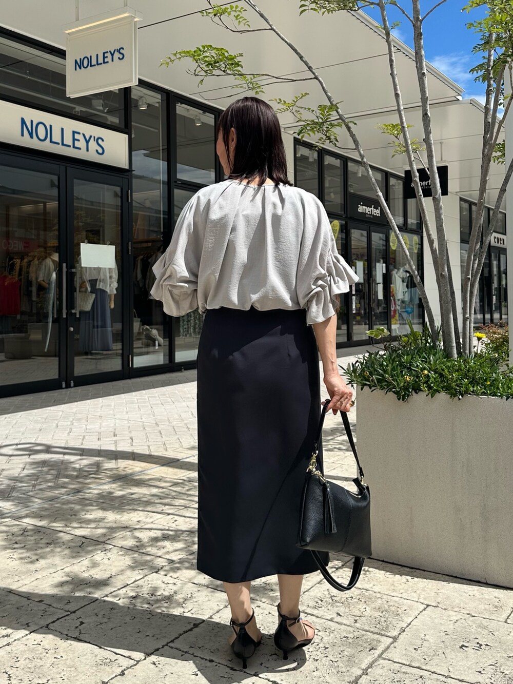 ブラック系のサンダル、ベージュ系のシャツ/ブラウス、ブルー系のスカートを着用したレディースの夏コーディネートの3枚目の写真