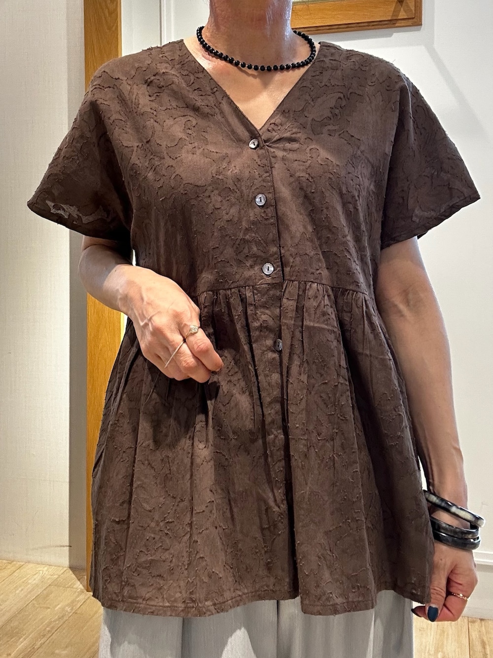ブラウン系のシャツ/ブラウス、グレー系のその他パンツ、ゴールド系のトートバッグを着用したレディースの夏コーディネートの9枚目の写真