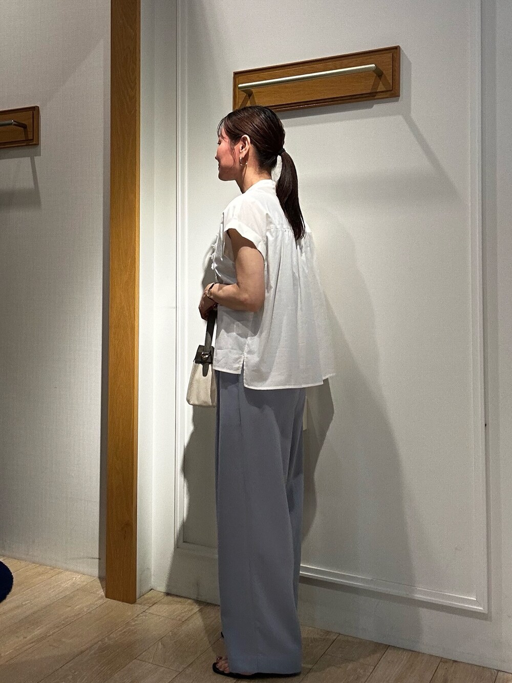 グレー系のダウンジャケット/コート、ホワイト系のシャツ/ブラウス、ベージュ系のショルダーバッグを着用したレディースの夏コーディネートの2枚目の写真