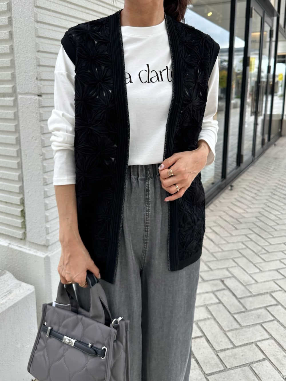 グレー系のデニムパンツ、ブラック系のニット/セーター、グレー系のトートバッグを着用したレディースの秋コーディネートの3枚目の写真