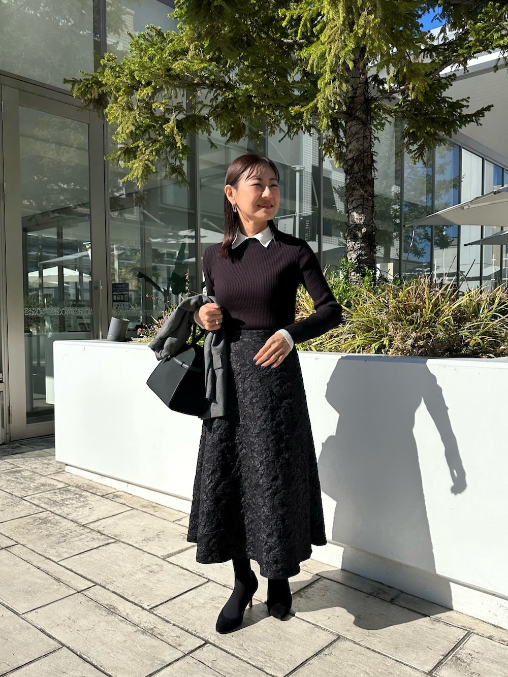 グレー系のブルゾン、ブラック系のニット/セーター、グレー系のスカートを着用したレディースの秋コーディネートの9枚目の写真