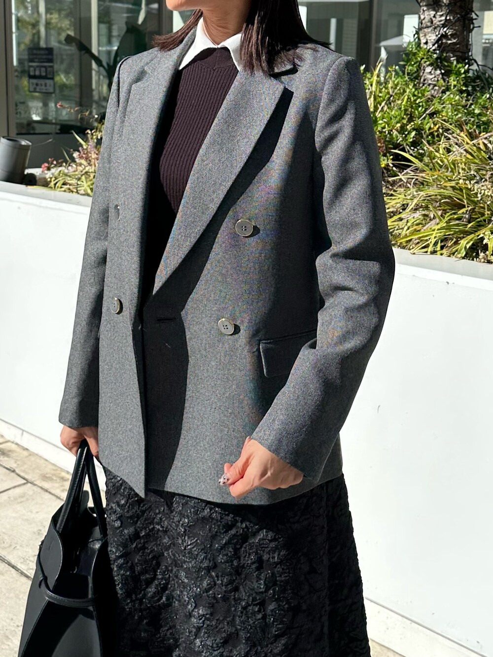 グレー系のテーラードジャケット、ブラック系のニット/セーター、グレー系のスカートを着用したレディースの秋コーディネートの5枚目の写真