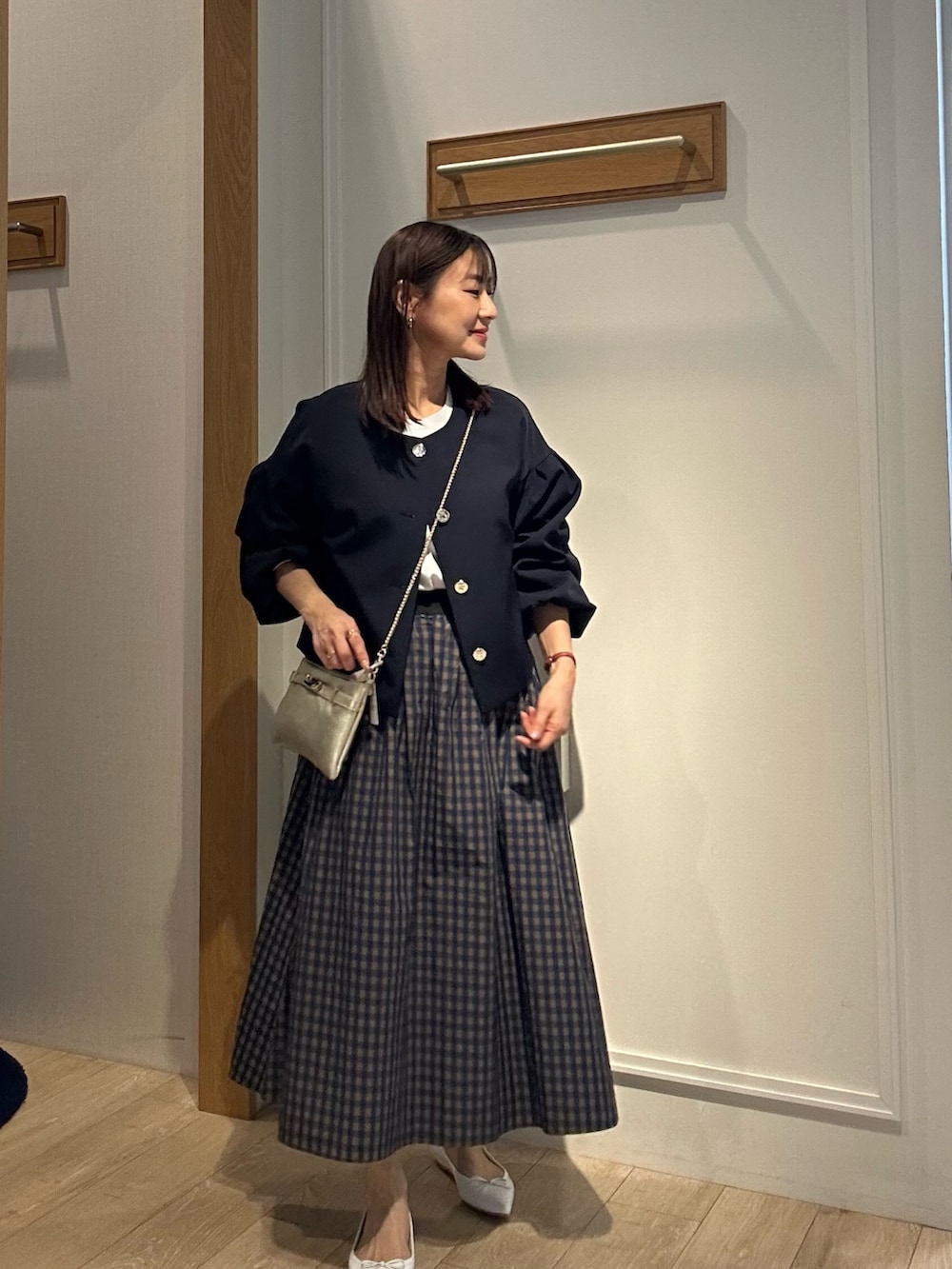 ブルー系のノーカラージャケット、ホワイト系のTシャツ/カットソー、ブラウン系のスカートを着用したレディースの冬コーディネートの2枚目の写真