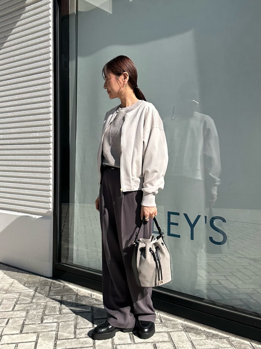 グレー系のその他パンツ、グレー系のニット/セーター、ベージュ系のブルゾンを着用したレディースの秋コーディネートの2枚目の写真