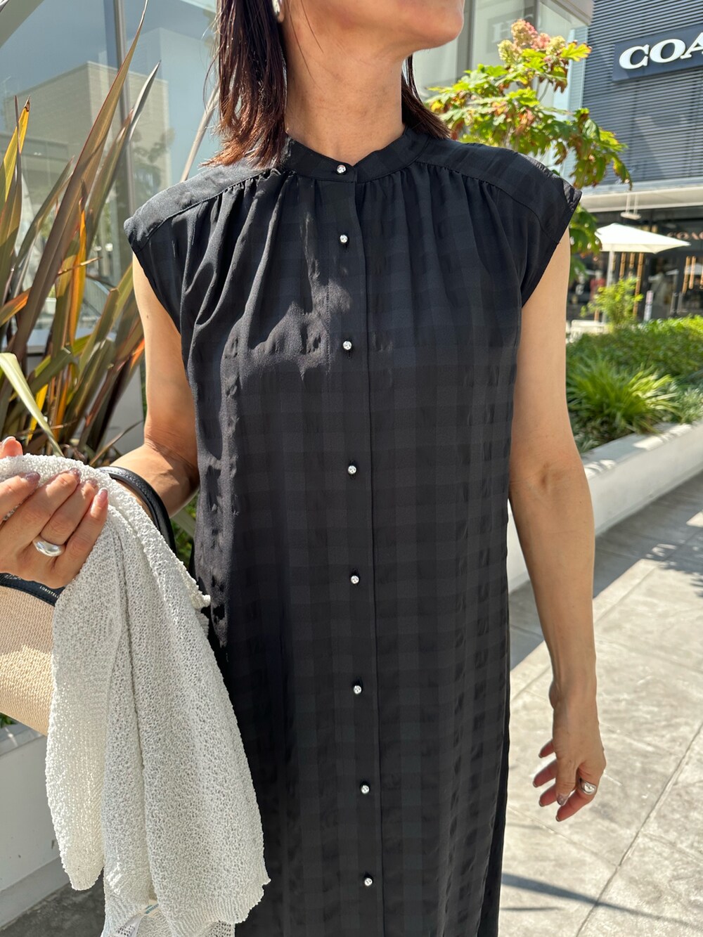 ブラック系のワンピース、ブラック系のサンダル、ホワイト系のカーディガン/ボレロを着用したレディースの夏コーディネートの4枚目の写真