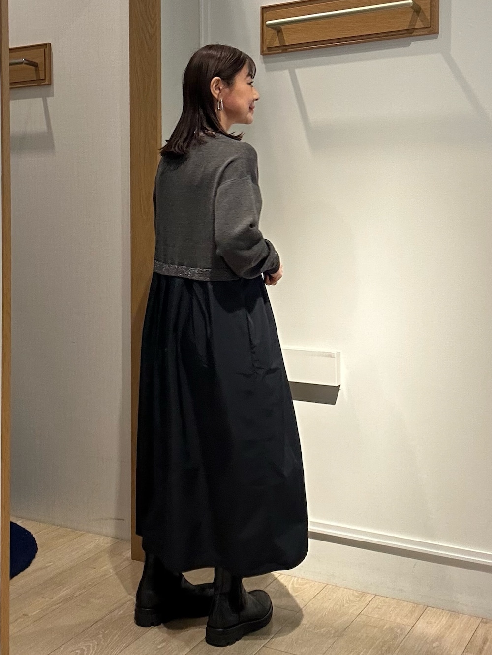 グレー系のワンピース、ゴールド系のショルダーバッグを着用したレディースの冬コーディネートの2枚目の写真