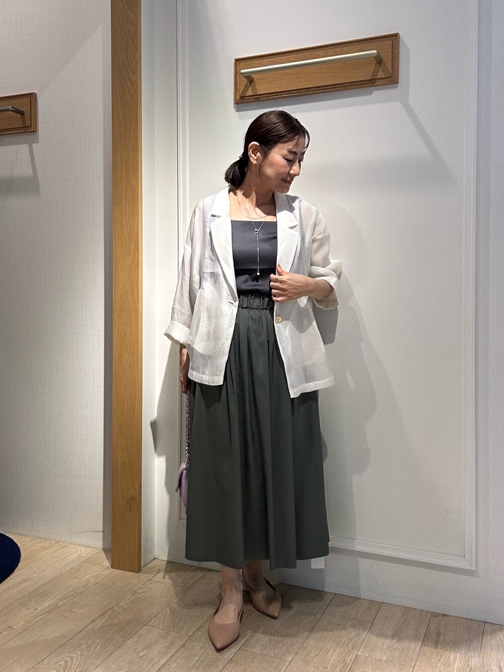 グレー系のTシャツ/カットソー、ホワイト系のテーラードジャケット、ブラック系のスカートを着用したレディースの春コーディネートの3枚目の写真