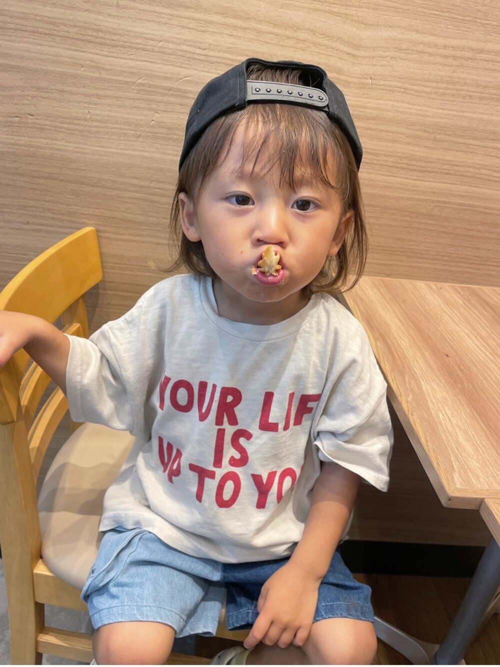 ベージュ系のトップス、ブルー系のパンツ、ブラック系のキャップを着用したキッズの秋コーディネートの2枚目の写真