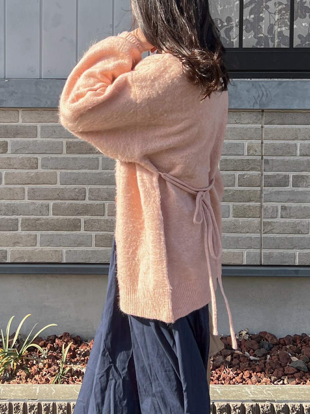 ブラウン系のカーディガン/ボレロ、ブルー系のスカート、ブラック系のパンプスを着用したレディースの冬コーディネートの2枚目の写真