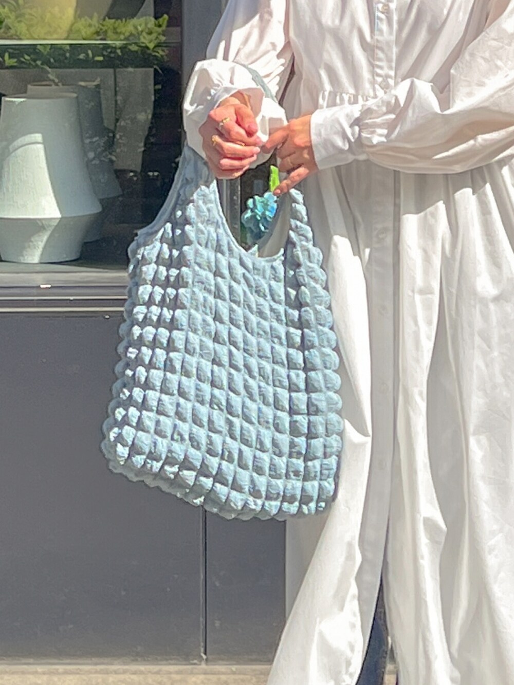 ブルー系のトートバッグを着用したレディースの春コーディネートの2枚目の写真