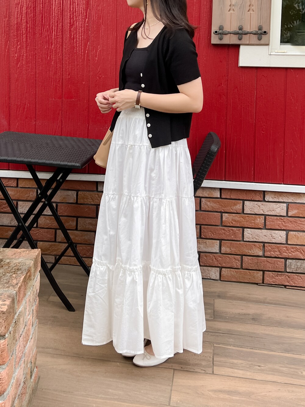 ブラック系のカーディガン/ボレロ、ホワイト系のスカート、ベージュ系のショルダーバッグを着用したレディースの夏コーディネートの3枚目の写真