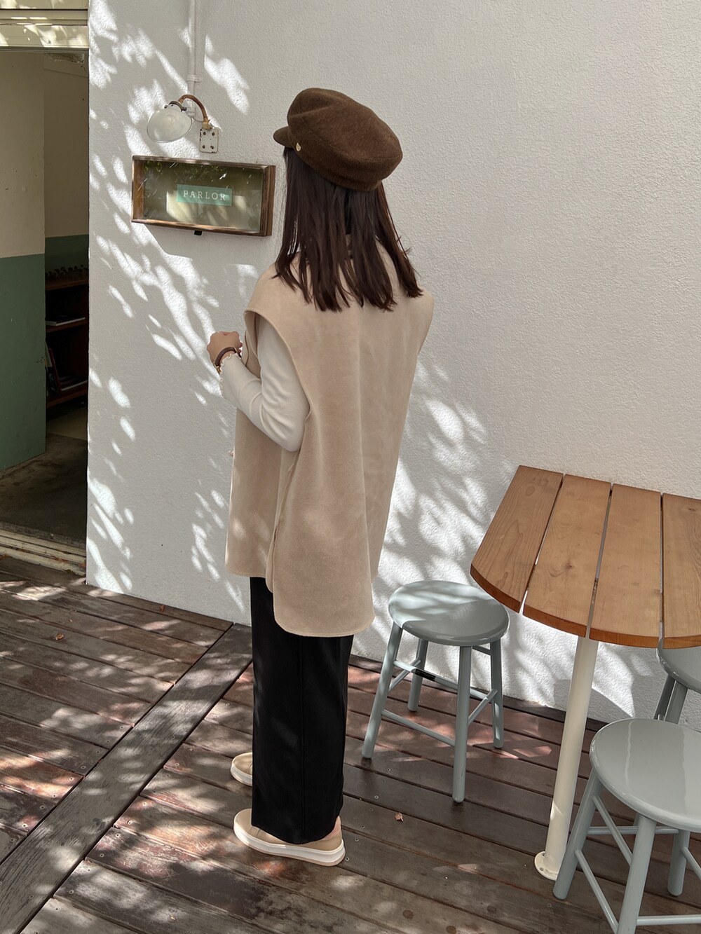 ブラック系のスカート、ベージュ系のベスト、ホワイト系のニット/セーターを着用したレディースの秋コーディネートの2枚目の写真