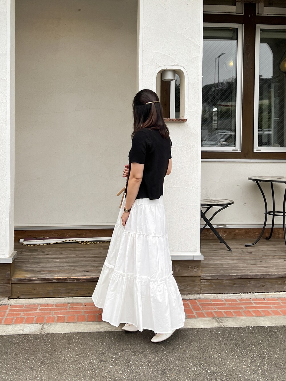 ブラック系のカーディガン/ボレロ、ホワイト系のスカート、ベージュ系のショルダーバッグを着用したレディースの夏コーディネートの2枚目の写真