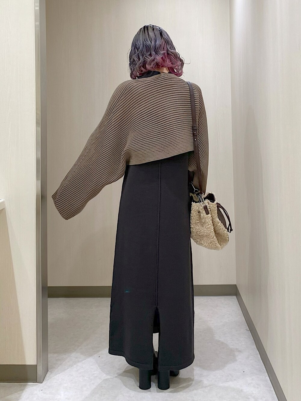 グレー系のワンピース、ベージュ系のショルダーバッグ、ブラック系のブーツを着用したレディースの冬コーディネートの3枚目の写真